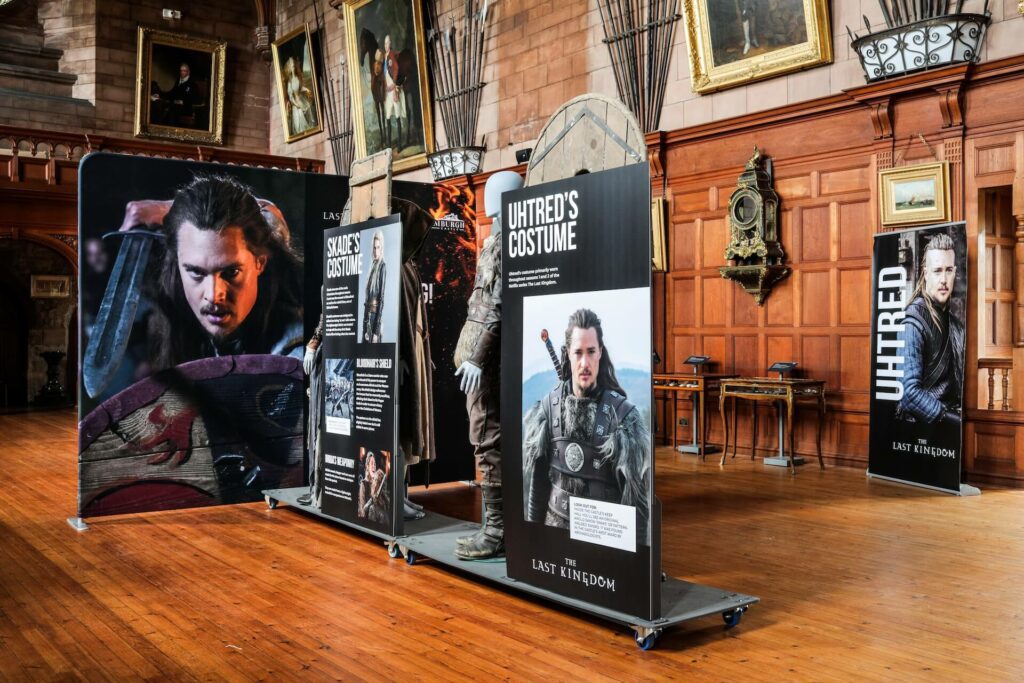 Stands at Bamburgh Castle, promoting the TV show The Last Kingdom.