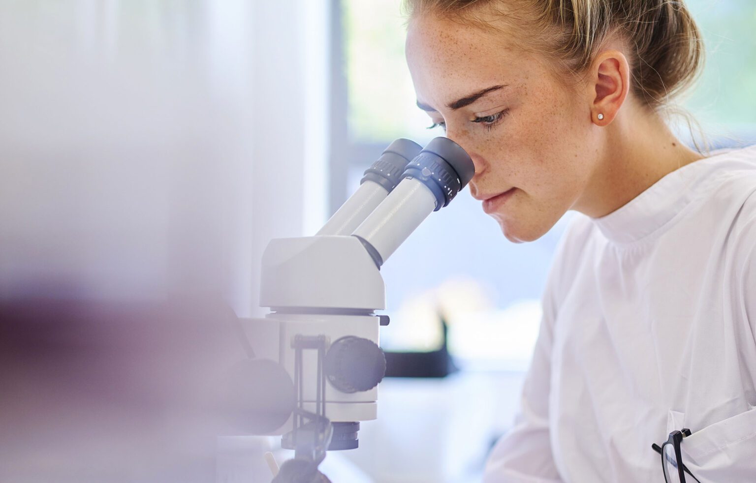Photo of lady looking through a microscope in a laboratory