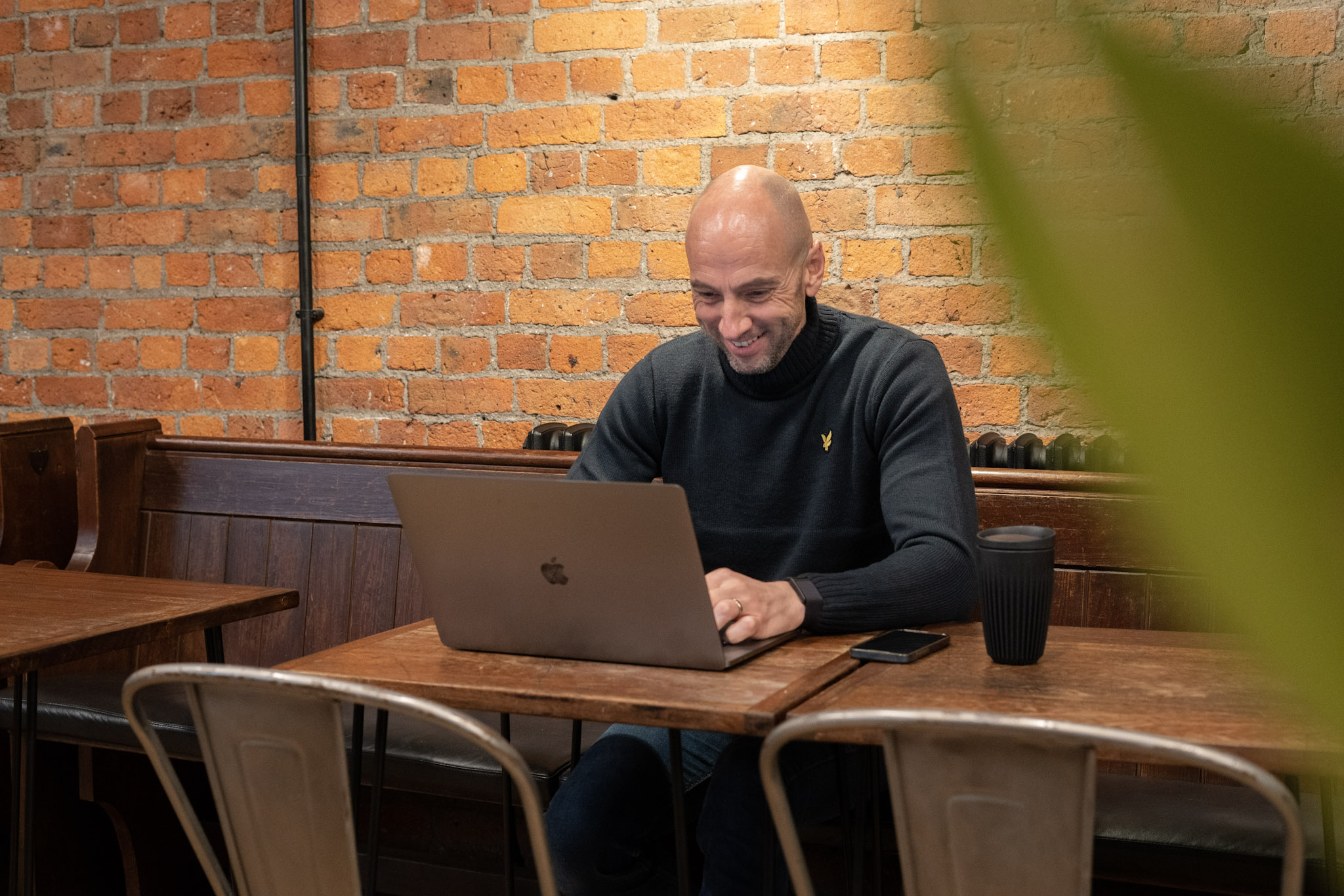 Ultimate CEO Richard Newman smiles at a laptop in a cafe.