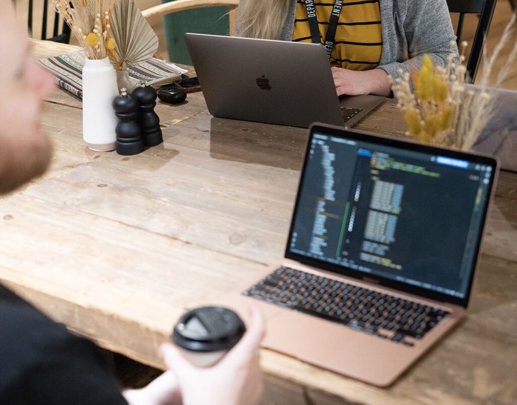 Employees coding a website at a communal office table.