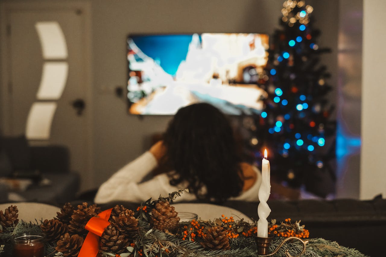 Woman watching TV with a Christmas tree beside her