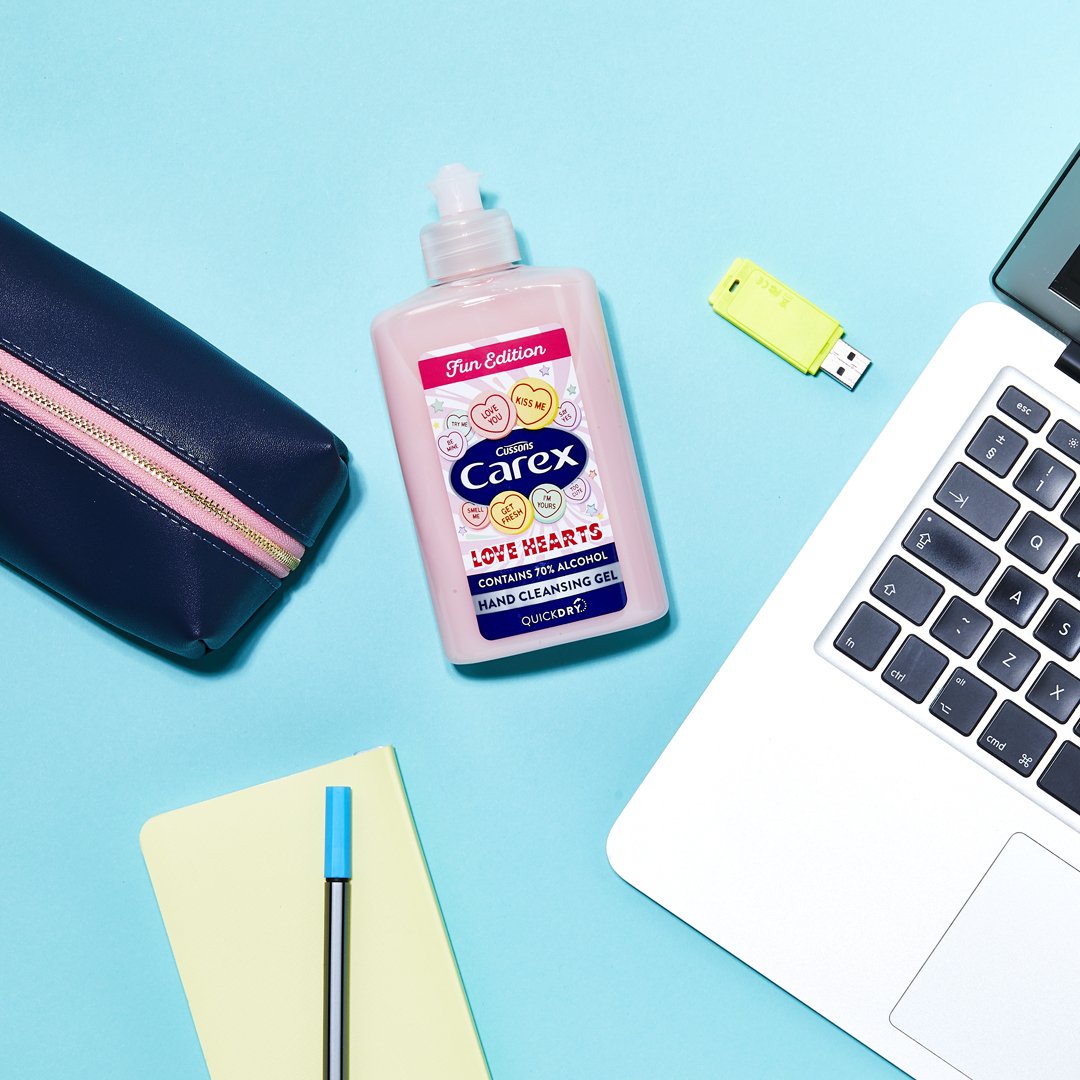 Carex Love Hearts mini hand sanitiser next to a laptop and pencil case.