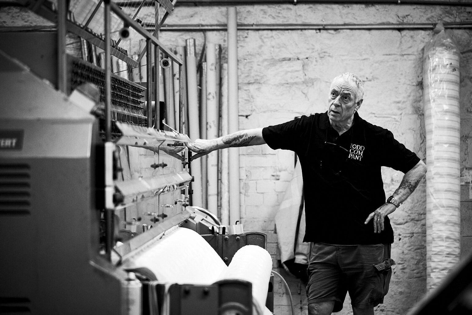 A mattress maker stands against an industrial machine.